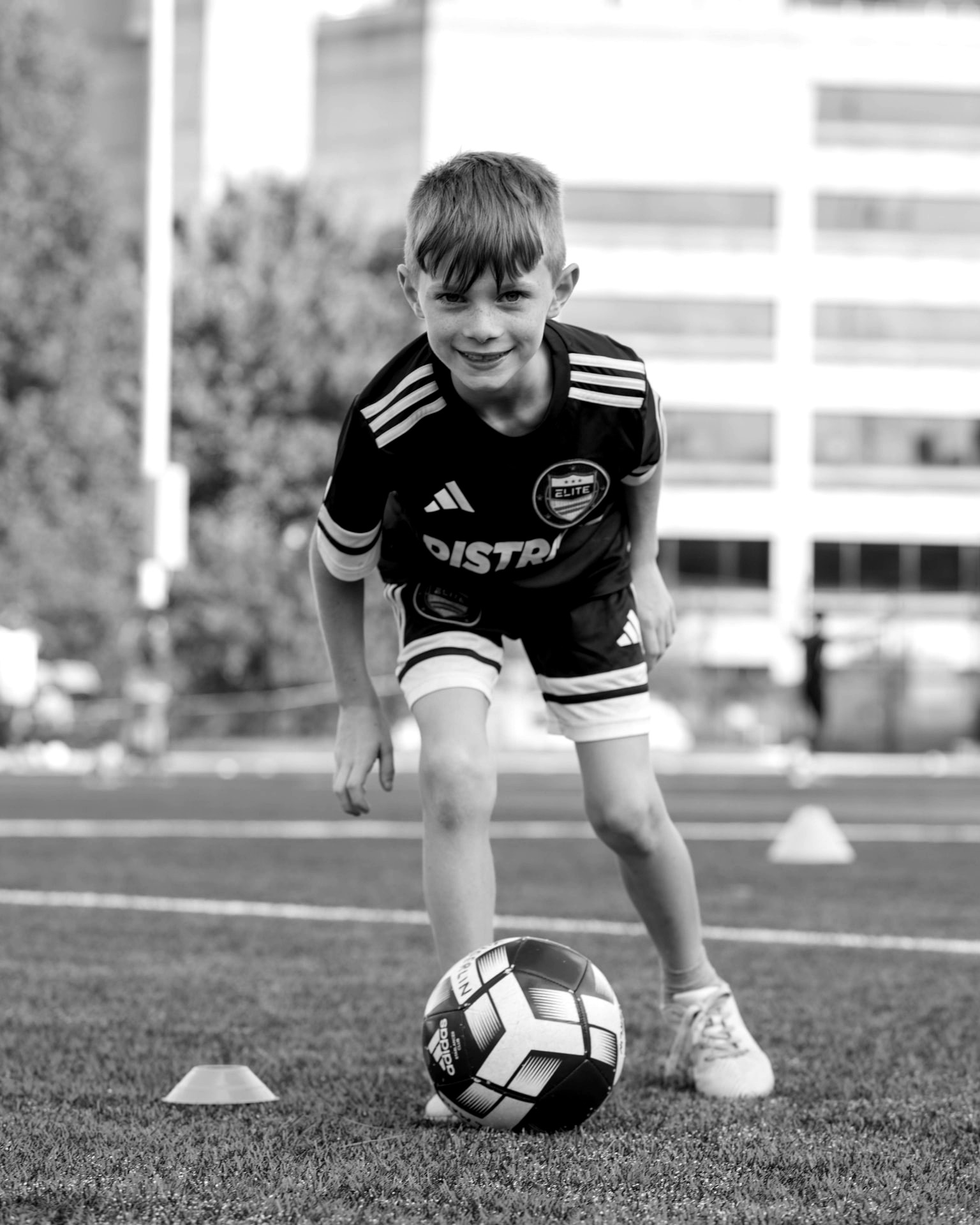 Young player smiling while controlling the ball during training